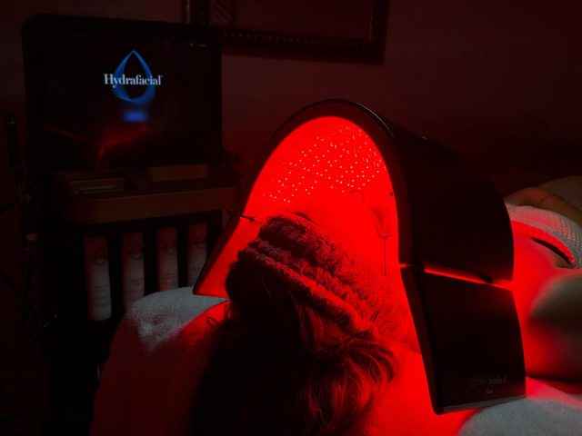 A red LED light dome over a client’s face during a facial at The Med Spa Wimberley